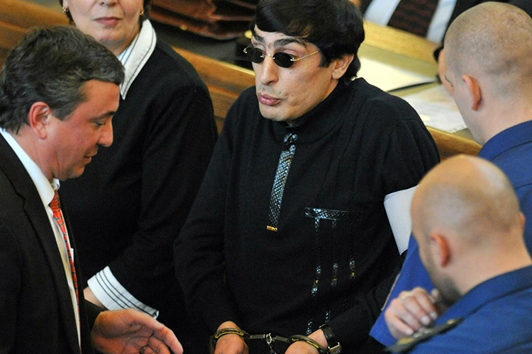 Андранік Согоян в чорній сорочці, темних окулярах і наручниках під час розгляду його справи в празькому суді
