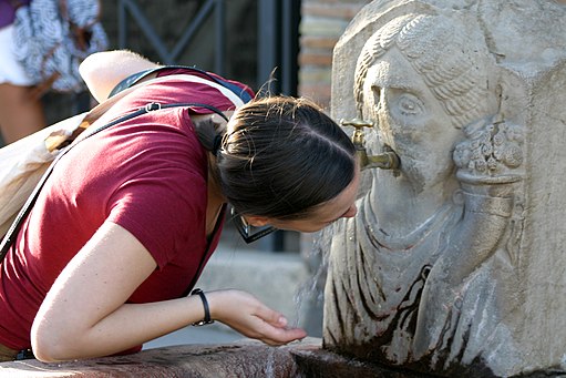Туристка п'є з вуличного фонтану в Помпеях: